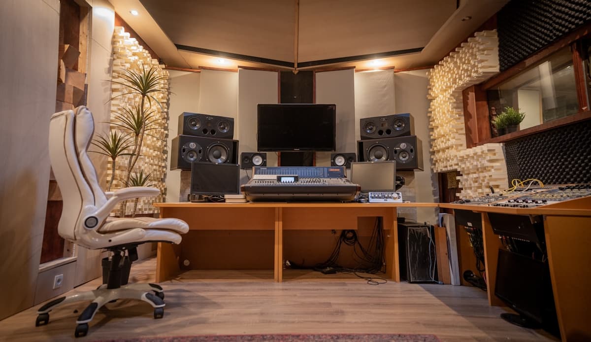 A creator's studio with studio monitors, a mixing desk, and acoustic treatment