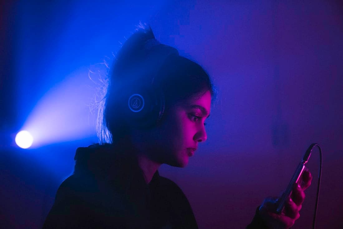 A streamer at a desk lit in blue, wearing headphones