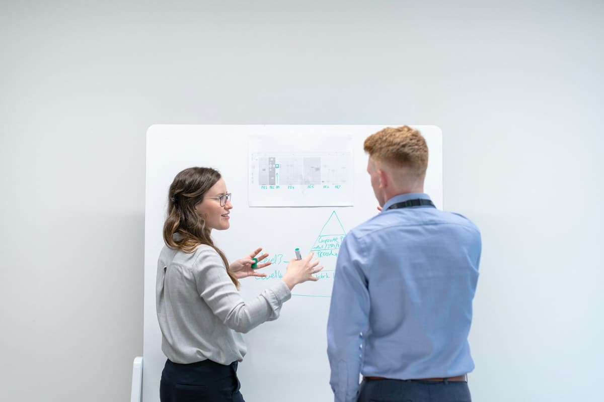 two colleagues discussing ideas at whiteboard