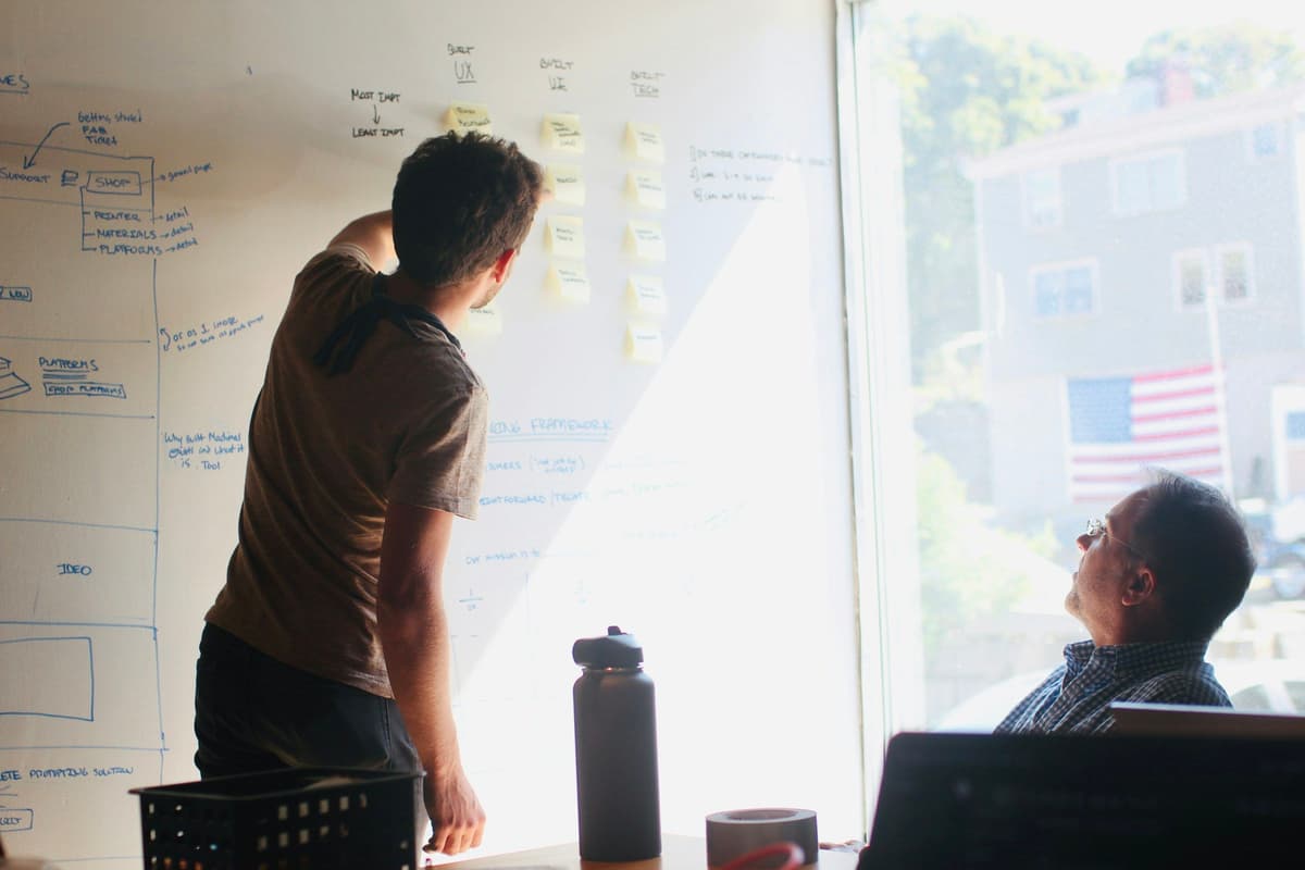 man in gray crew neck t-shirt standing near whiteboard