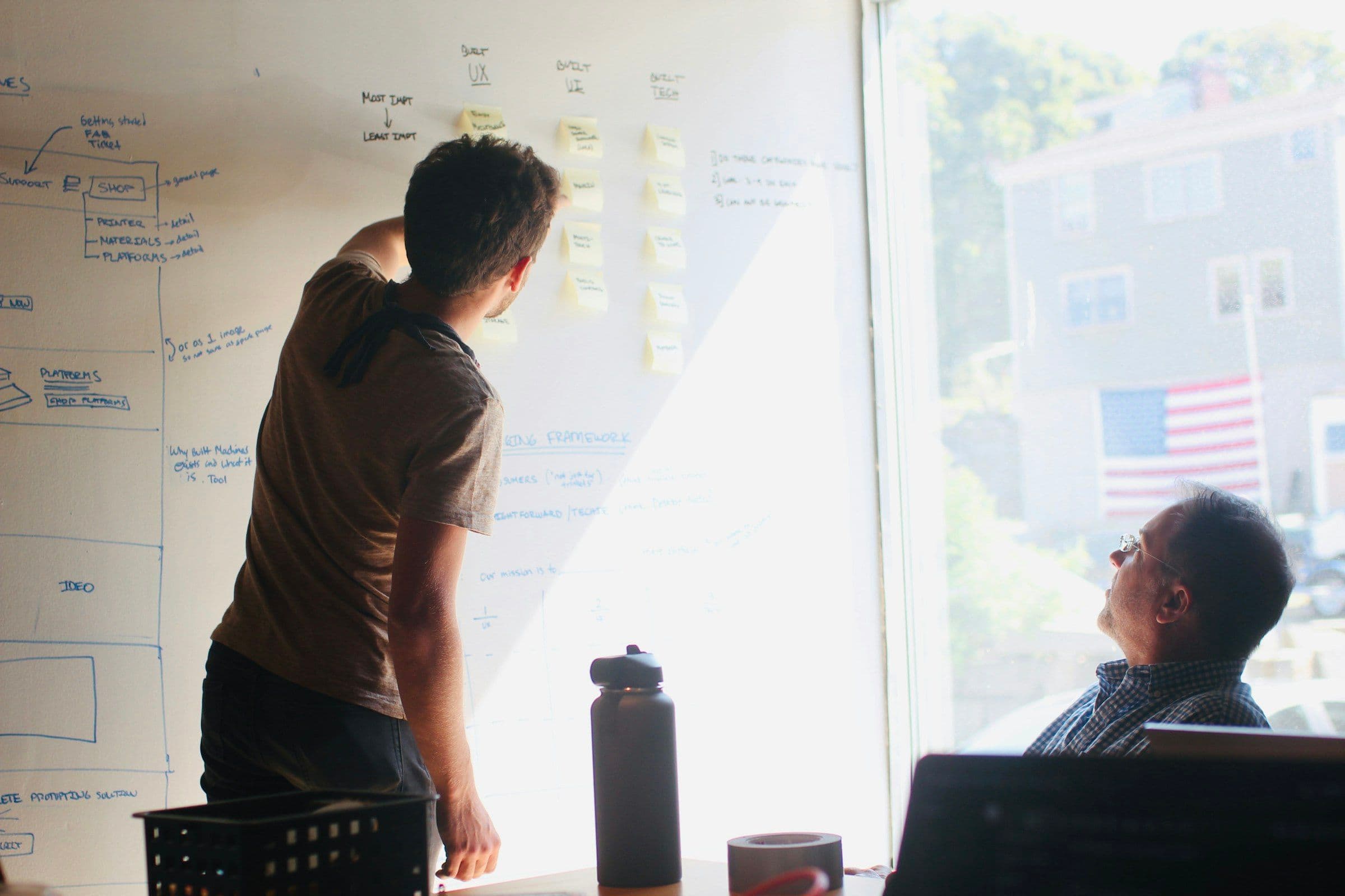 man in gray crew neck t-shirt standing near whiteboard
