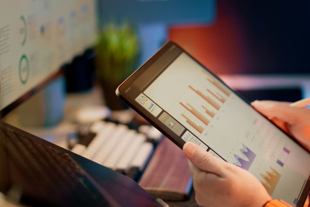 Someone analyzes financial data on a tablet.
